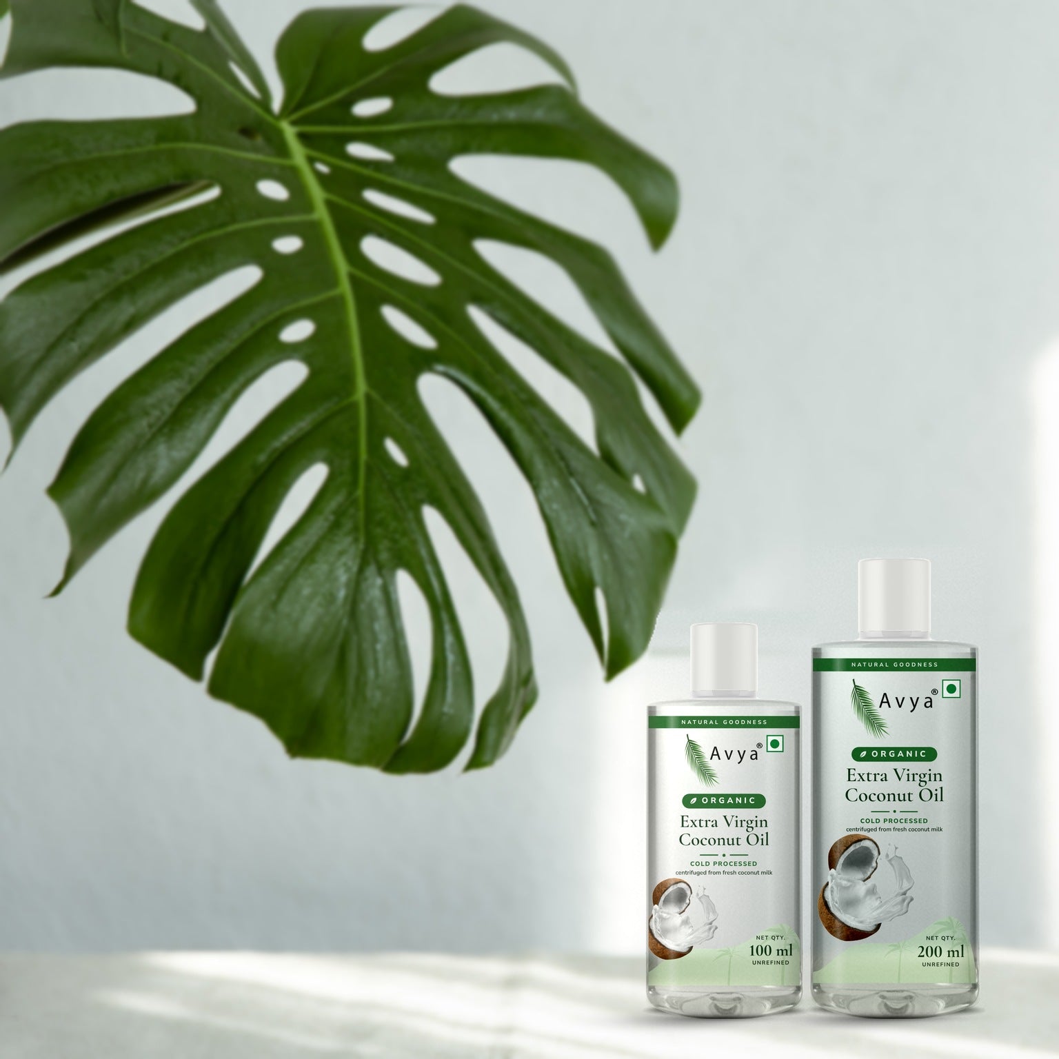 Avya Organic Extra Virgin Coconut Oil 100 ml and 200 ml with a monstera leaf